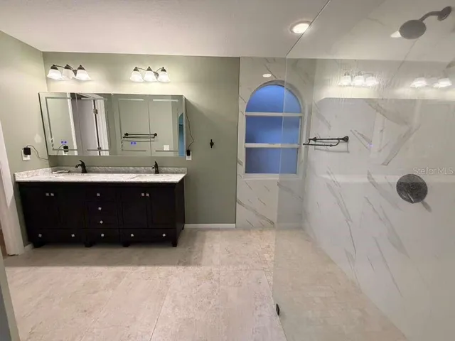 a bathroom with a double vanity sink a mirror and shower