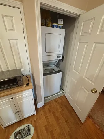 a utility room with wooden floor and washer