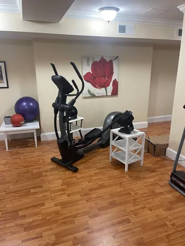 a room with gym equipment and wooden floor