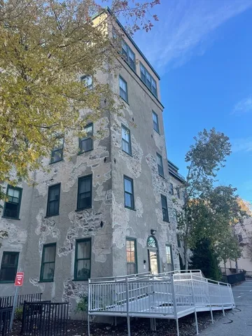 a front view of a house with large trees