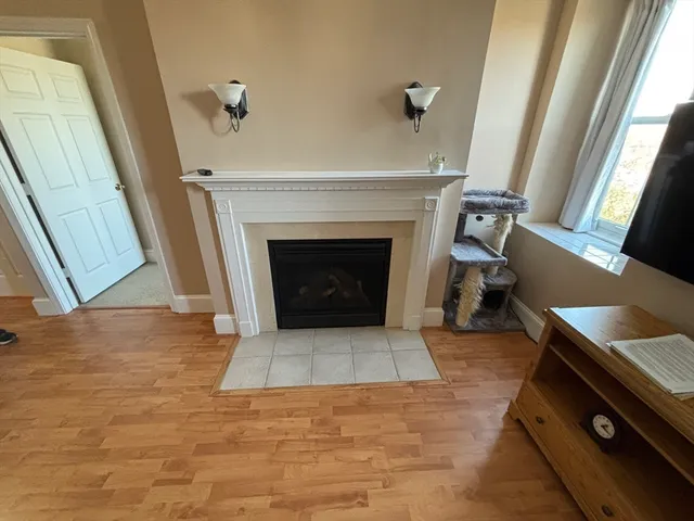 a view of an empty room with wooden floor and a fireplace