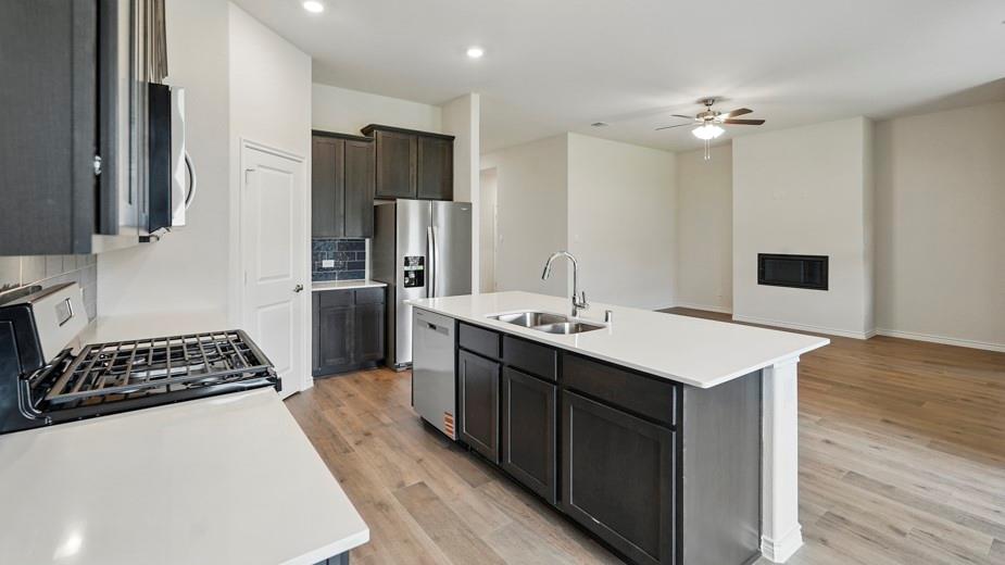 4162 Waldron Trail Forney, TX 75126 - Photo 2 of 29 Open-concept living space with a kitchen island featuring a double-basin sink and stainless steel appliances