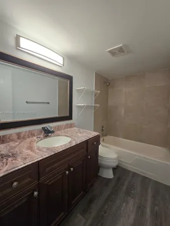 a bathroom with a granite countertop sink a toilet and a bathtub