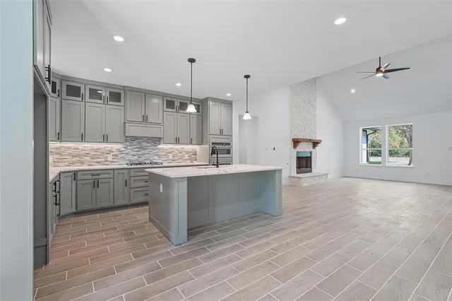 a large white kitchen with kitchen island a sink stainless steel appliances and cabinets