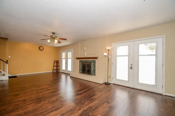 an empty room with wooden floor chandelier and windows