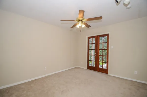 an empty room with windows and fan