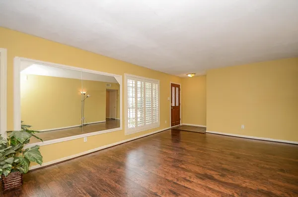 a view of an empty room with wooden floor and a window