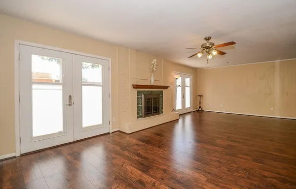 a view of an empty room with a window and wooden floor