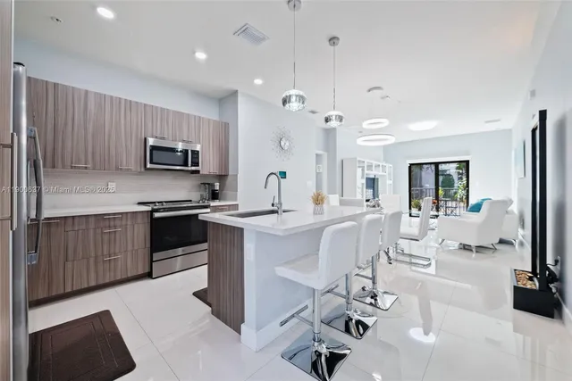 a kitchen with kitchen island granite countertop a sink counter top space appliances and cabinets