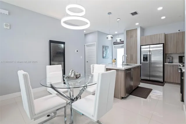 a kitchen with stainless steel appliances kitchen island granite countertop a table chairs and a refrigerator