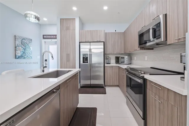 a kitchen with stainless steel appliances granite countertop a sink a stove a refrigerator cabinets and a kitchen island