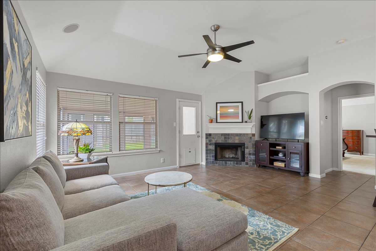 9012 Meacham Way Austin, TX 78749 - Photo 15 of 34 Spacious living area featuring a vaulted ceiling with a ceiling fan, a tiled fireplace, and arched doorways