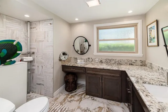 a bathroom with a granite countertop sink a toilet and a shower