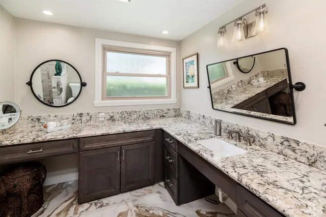 a bathroom with a granite countertop sink and a mirror