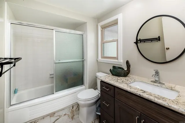 a bathroom with a granite countertop sink toilet mirror and shower
