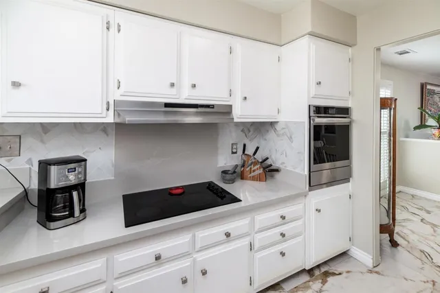 a kitchen with white cabinets and appliances