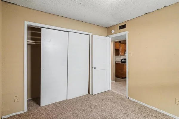 an empty room with closet and a hallway