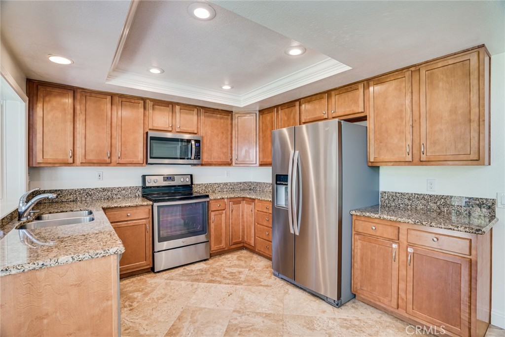 49 East Yale Loop, Unit 26 Irvine, CA 92604 - Photo 13 of 63 a kitchen with granite countertop stainless steel appliances a refrigerator stove top oven and sink
