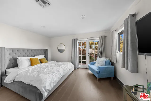 a bedroom with a bed couch and a flat tv screen