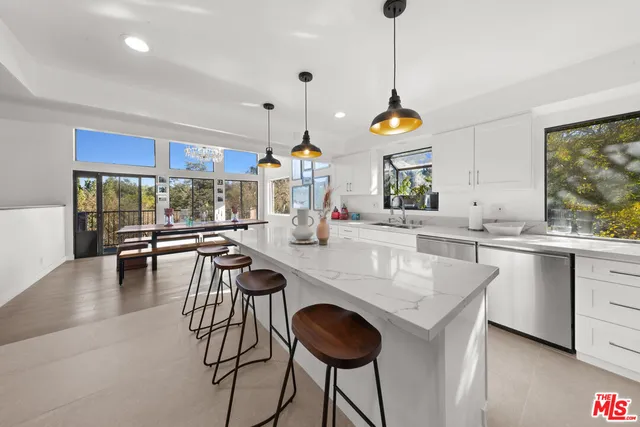 a kitchen with kitchen island granite countertop a stove a sink a dining table and chairs with wooden floor