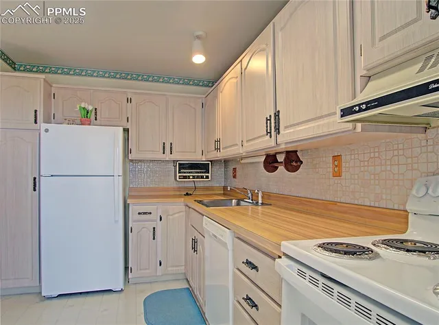 a kitchen with stainless steel appliances a refrigerator a sink and white cabinets