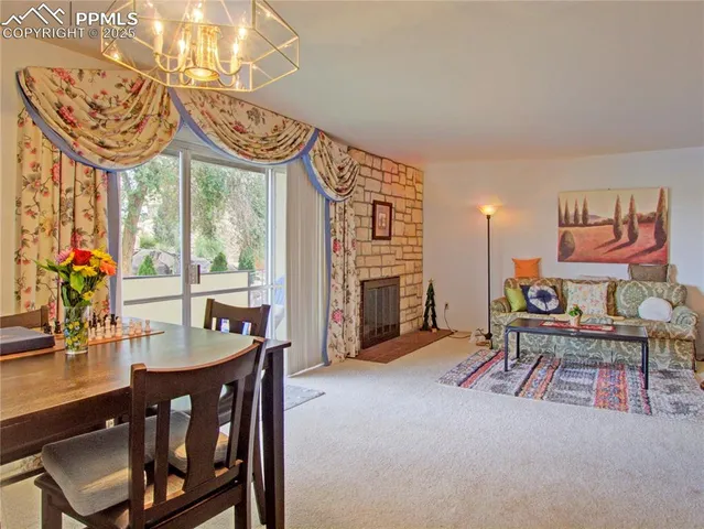 a very nice looking living room with a large window a fireplace and a chandelier