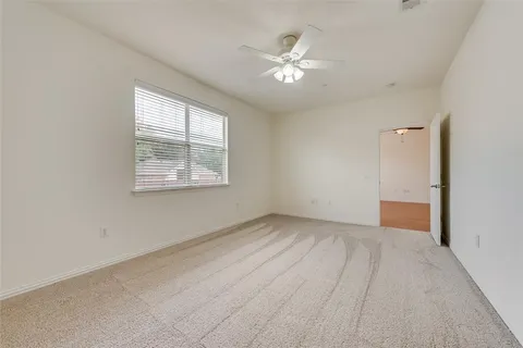 a view of an empty room with chandelier fan and fire place