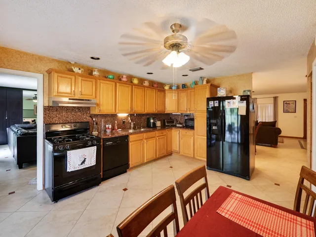 a kitchen with stainless steel appliances kitchen island granite countertop a refrigerator a sink a stove and white cabinets