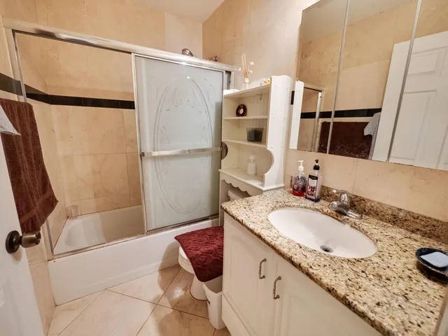a bathroom with a granite countertop sink a mirror and shower