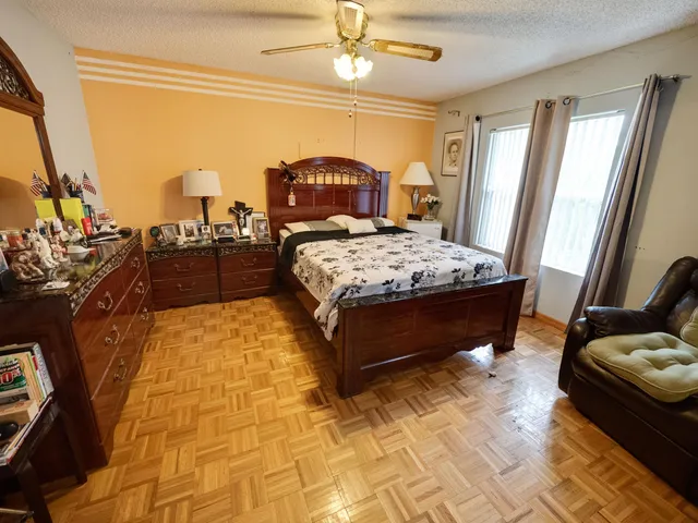 a bedroom with a bed dresser and a large window