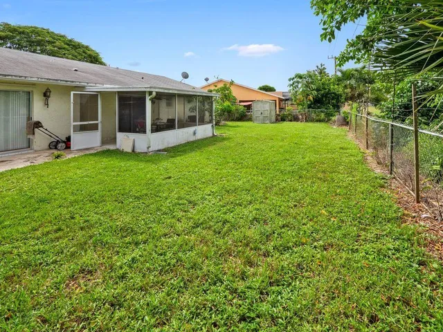 a view of a backyard with table and chairs potted plants and large tree