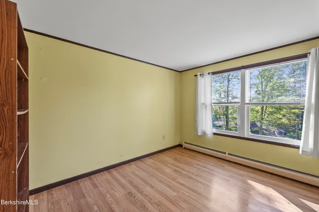 a view of an empty room with a window and wooden floor