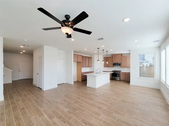 a view of a kitchen with kitchen island wooden floors appliances and a counter top space