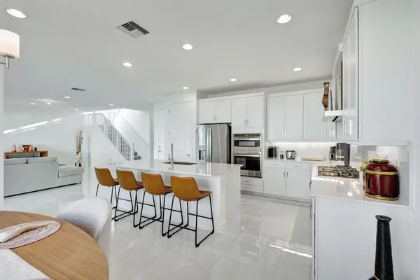 a kitchen with stainless steel appliances kitchen island granite countertop a sink and a refrigerator