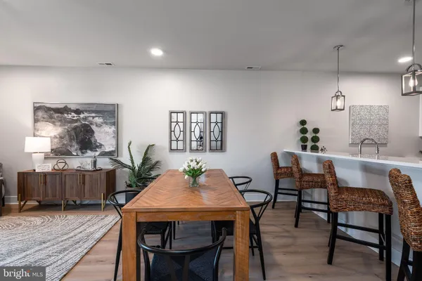 a kitchen with stainless steel appliances kitchen island a table chairs in it and wooden floors
