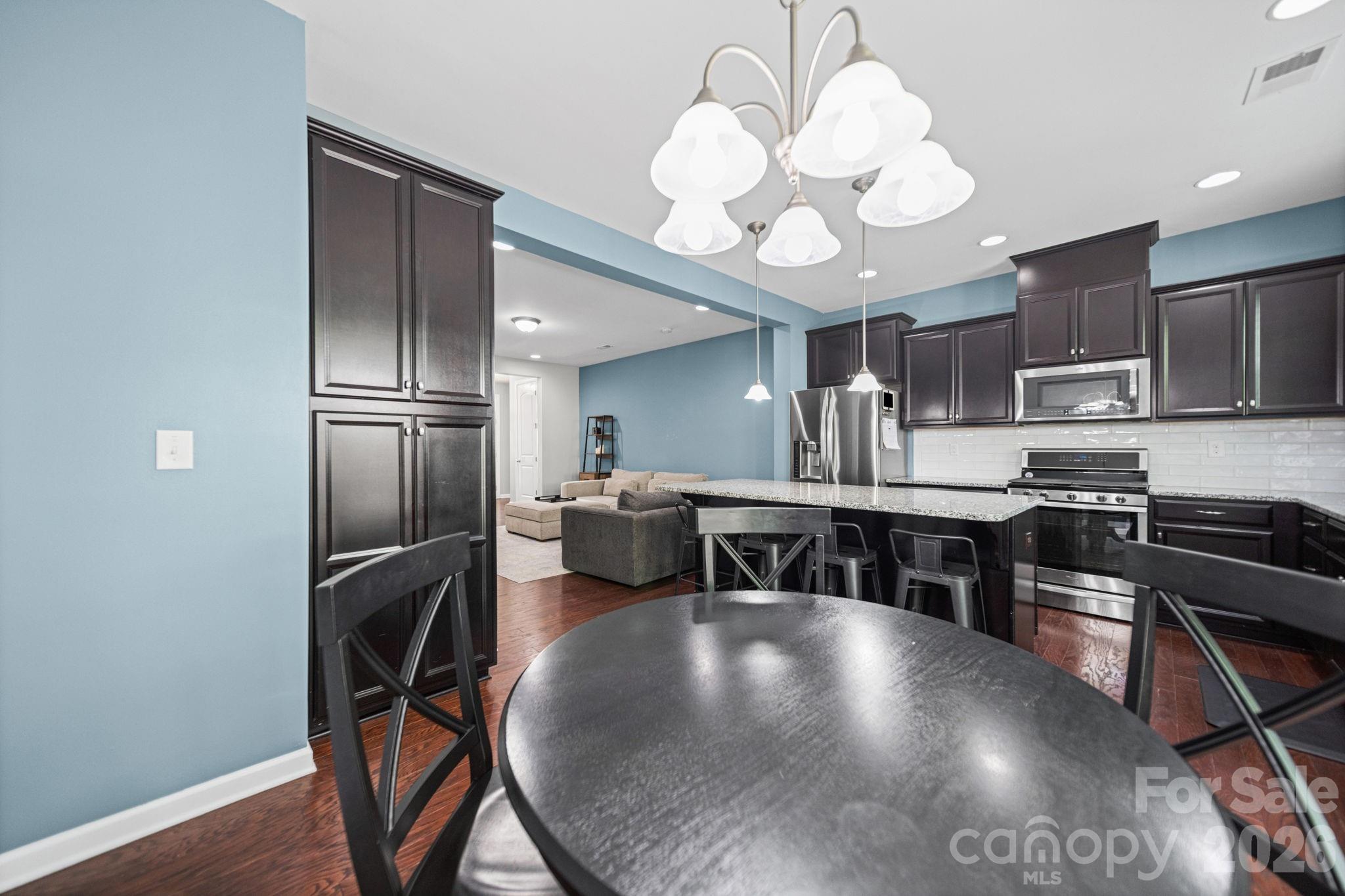 1108 Roderick Drive Fort Mill, SC 29708 - Photo 13 of 39 a kitchen with stainless steel appliances granite countertop a stove refrigerator a oven a dining table and chairs with wooden floor