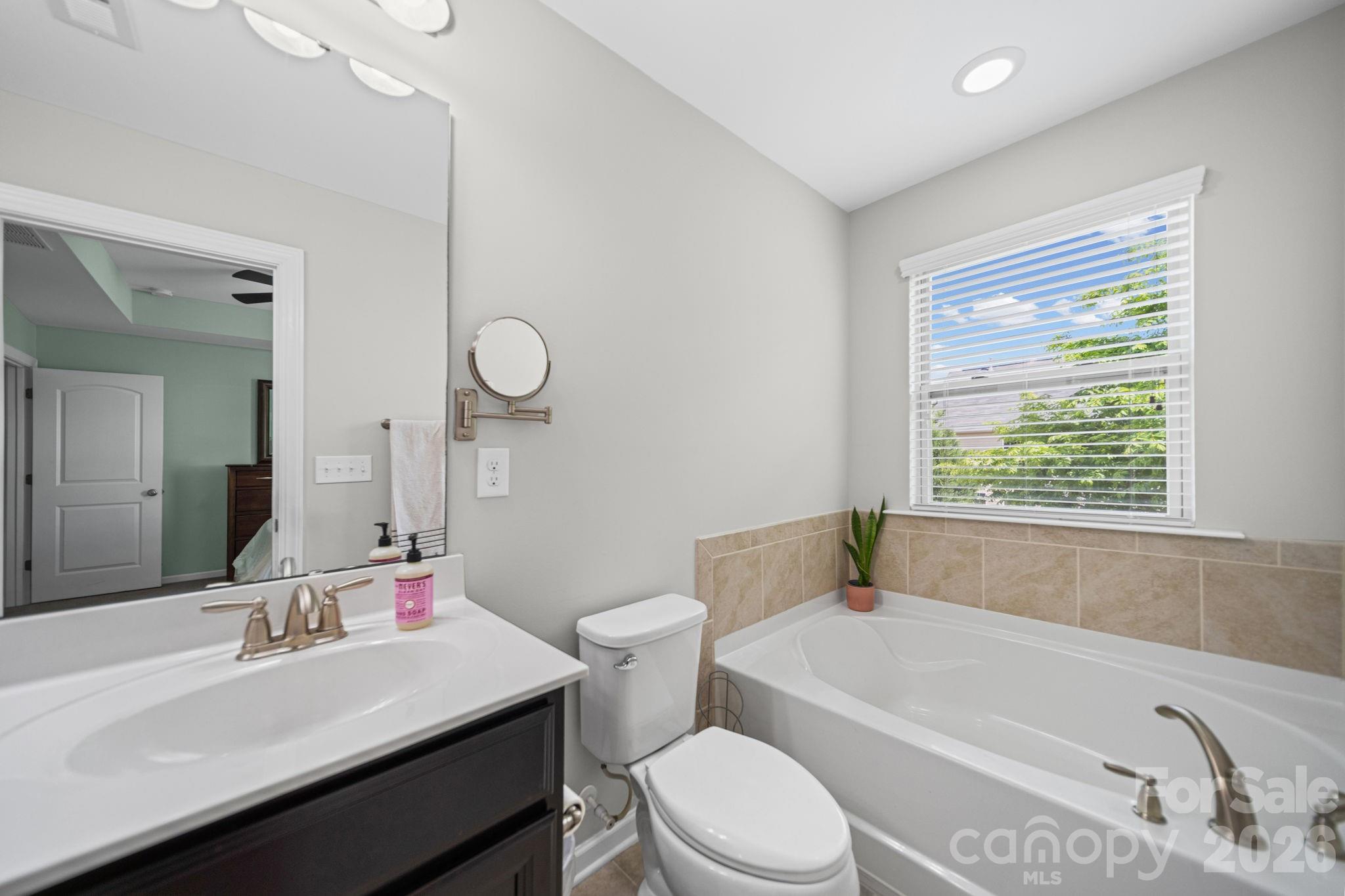 1108 Roderick Drive Fort Mill, SC 29708 - Photo 22 of 39 a bathroom with a sink a toilet a mirror a vanity a bathtub and next to a window