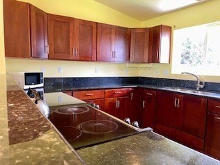 18-7856 Kaniela Road Mountain View, HI 96771 - Photo 3 of 30 a kitchen with wooden cabinets a sink and a stove