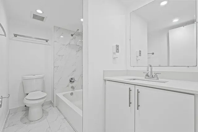 a bathroom with a granite countertop sink a toilet and shower