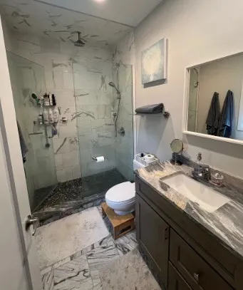 a bathroom with a granite countertop sink toilet and shower