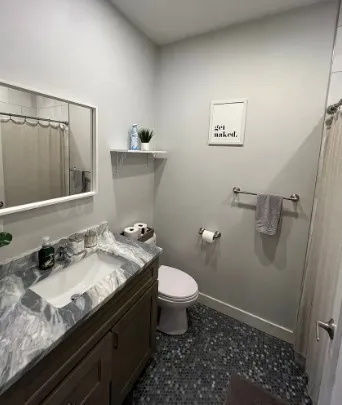 a bathroom with a granite countertop sink a toilet and a mirror