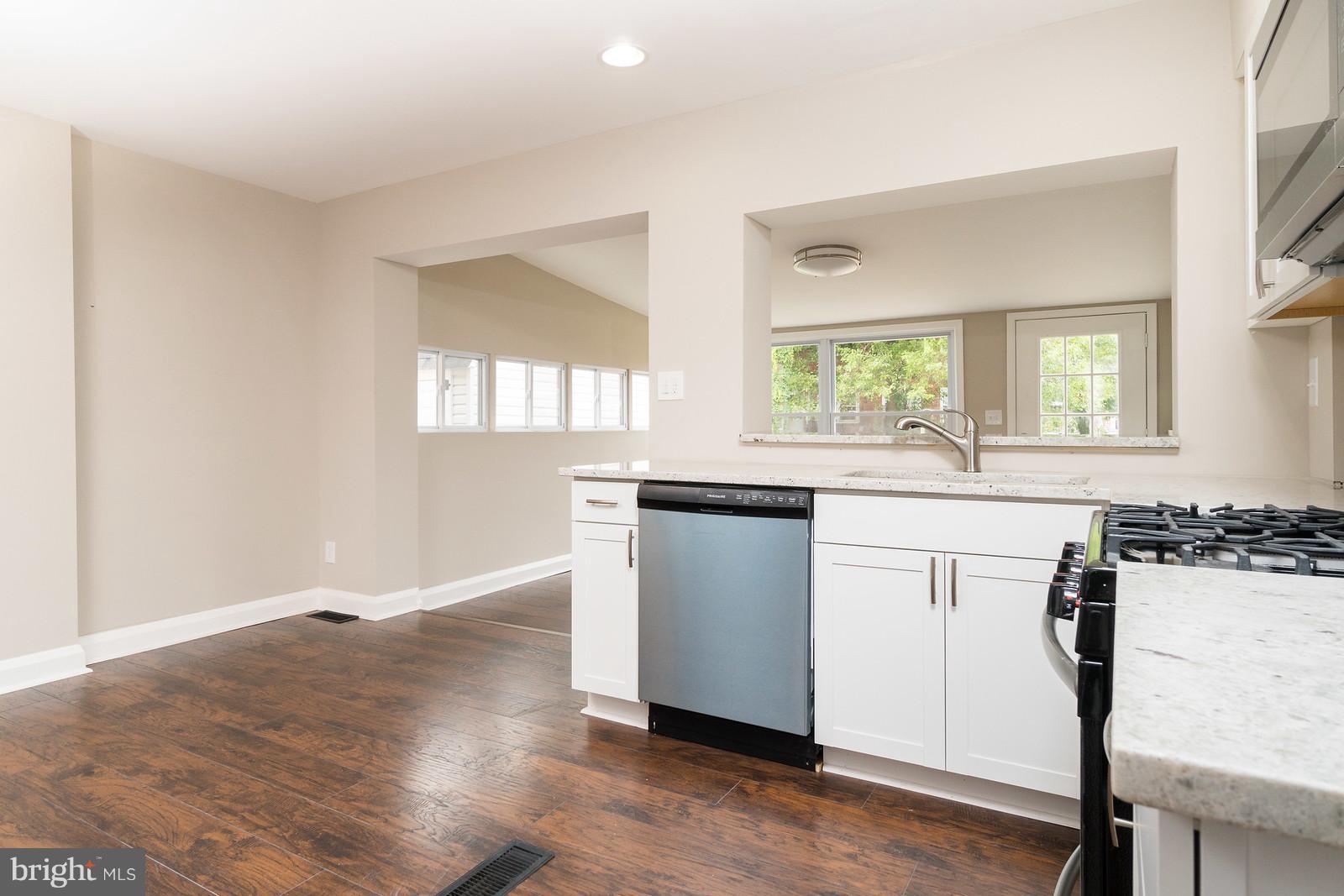 2113 Coralthorn Road Baltimore, MD 21220 - Photo 10 of 24 a kitchen with granite countertop a stove a sink and white cabinets with wooden floor