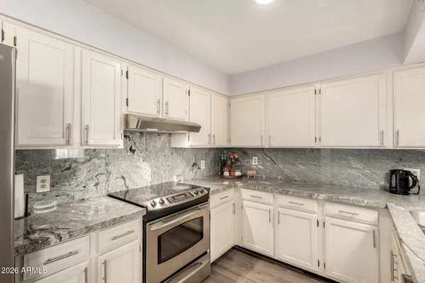 a kitchen with granite countertop white cabinets and white appliances