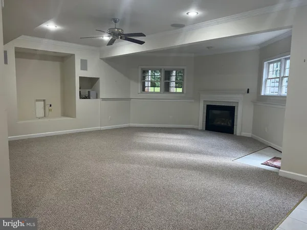 an empty room with windows and fireplace