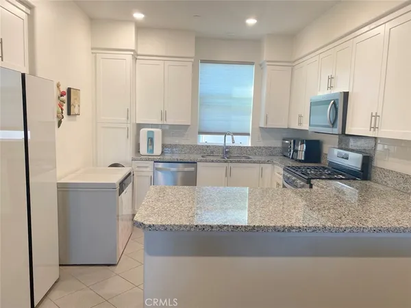 a kitchen with stainless steel appliances granite countertop a sink a stove and a refrigerator
