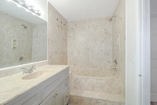 a bathroom with a granite countertop sink a shower and a mirror