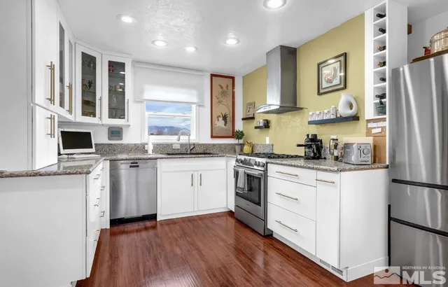 a kitchen with granite countertop a refrigerator a sink and white cabinets