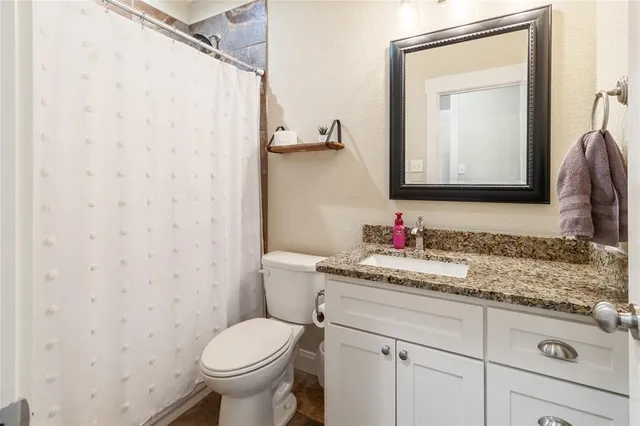a bathroom with a granite countertop toilet sink and mirror