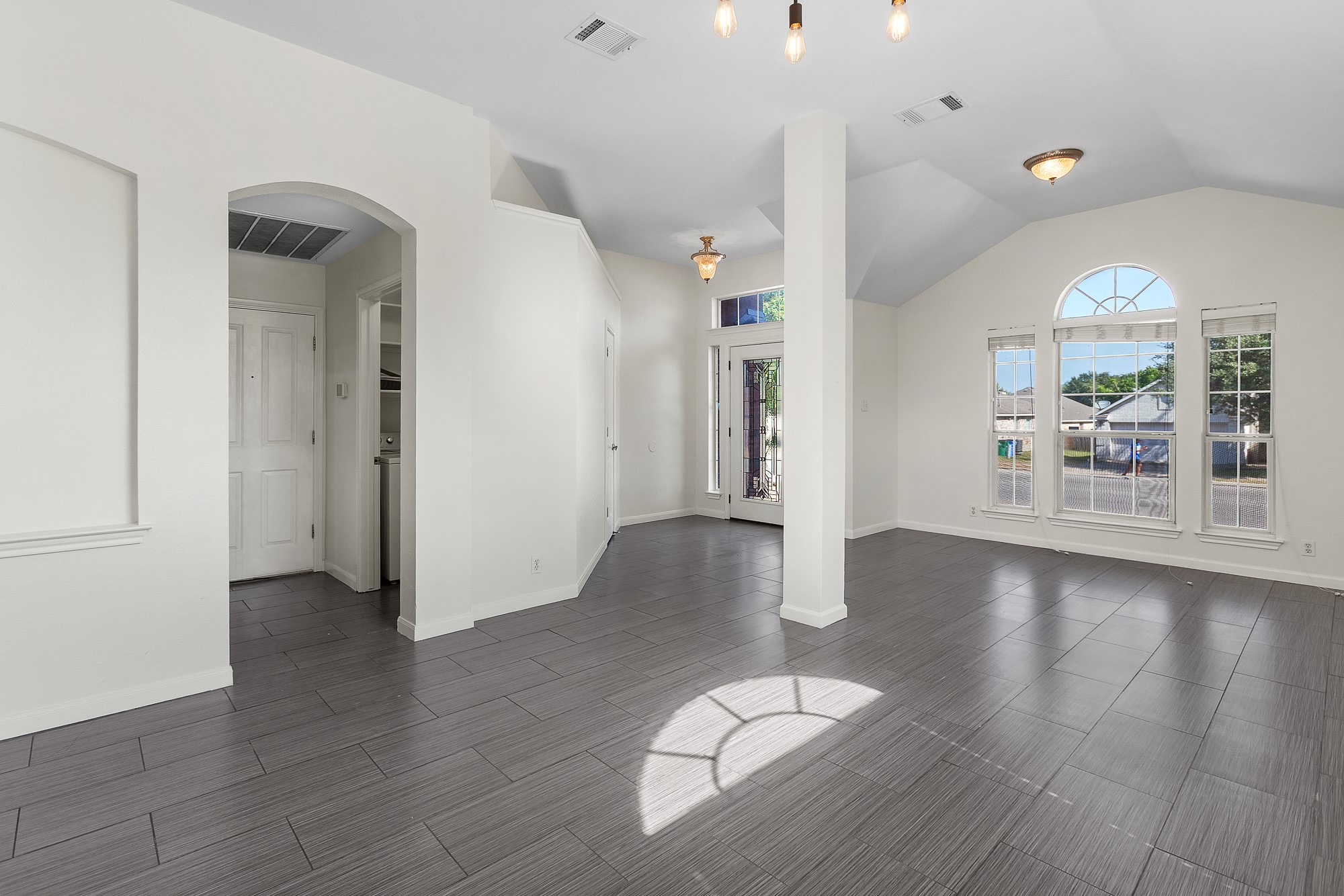 1201 Springbrook Road Pflugerville, TX 78660 - Photo 5 of 33 Natural light floods this inviting living space, highlighting the contemporary gray tile flooring and elegant vaulted ceilings.