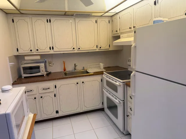 a kitchen with white cabinets and white appliances